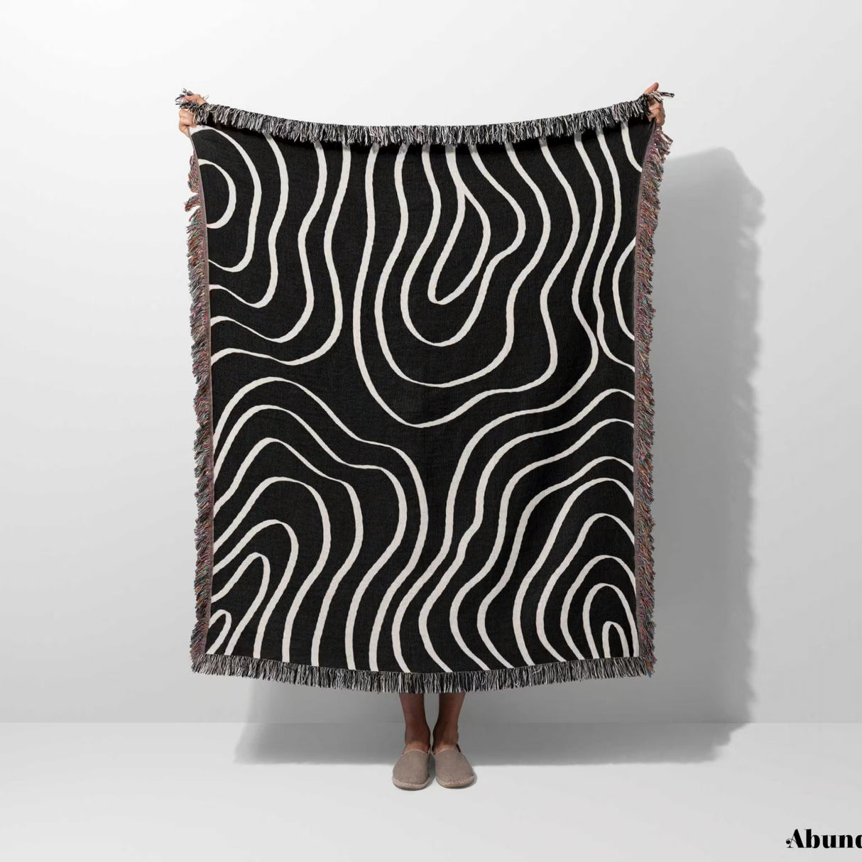 Black and white abstract art waves cotton woven blanket throw tapestry held by a person on a white background