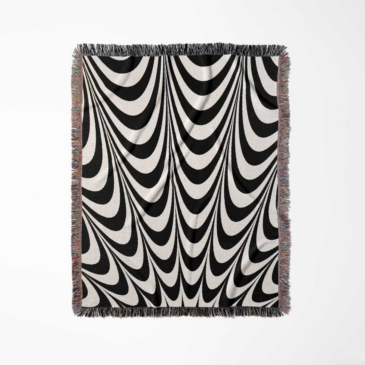 Black and white abstract art wavy woven blanket throw tapestry with fringe full view on a light gray background.