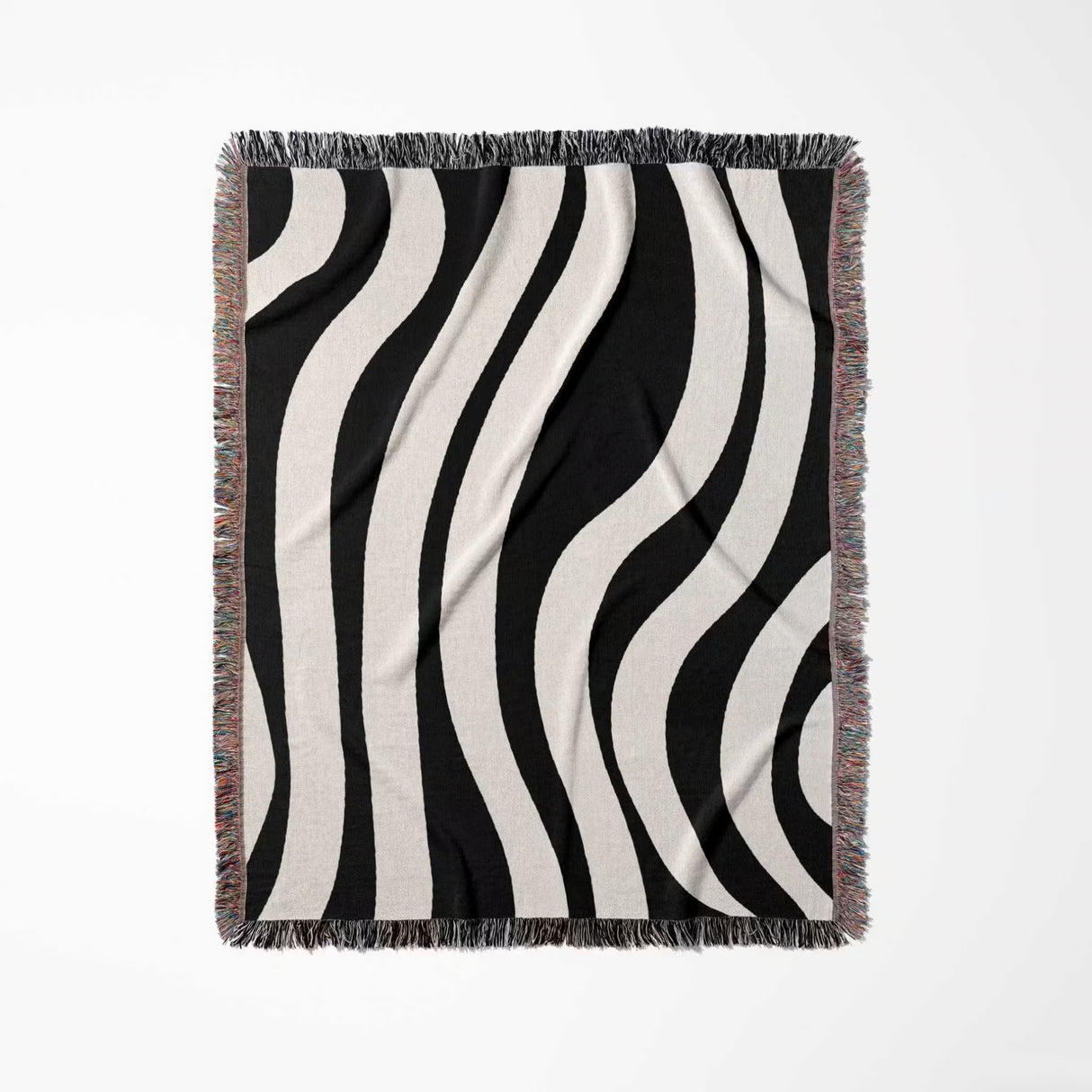 Black and white abstract shapes woven blanket throw tapestry with fringed edges full view on a light gray background.