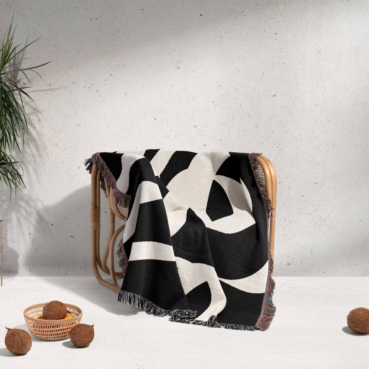 Black and white abstract waves accent woven blanket throw draped over a chair with a minimal background