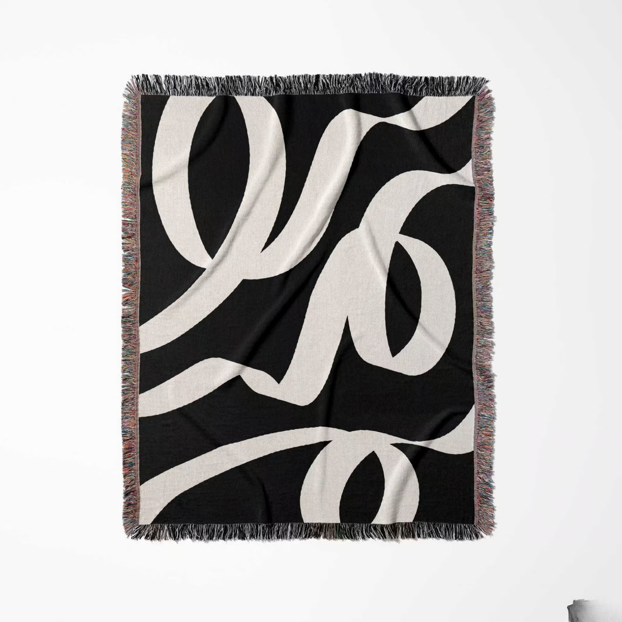 Black and white abstract waves accent woven blanket throw with fringe full view on a white background.