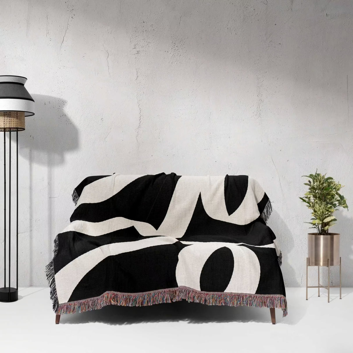 Black and white abstract waves accent woven blanket throw draped over a sofa against a light gray wall.