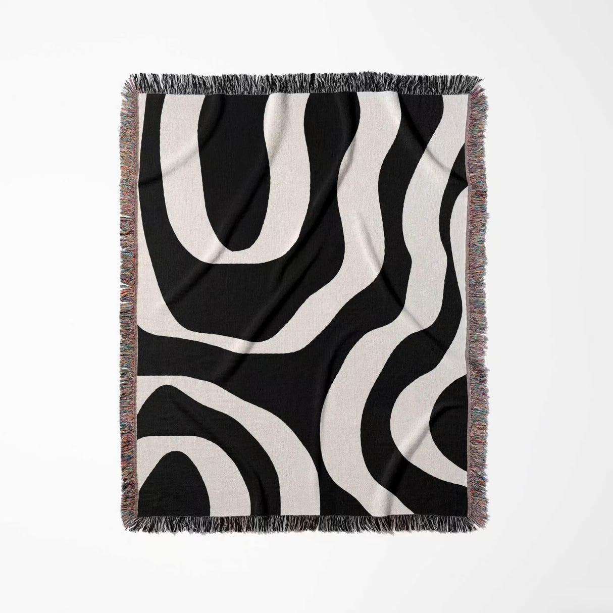 Black and white abstract waves aesthetic woven blanket throw with fringe full view on a light gray background.