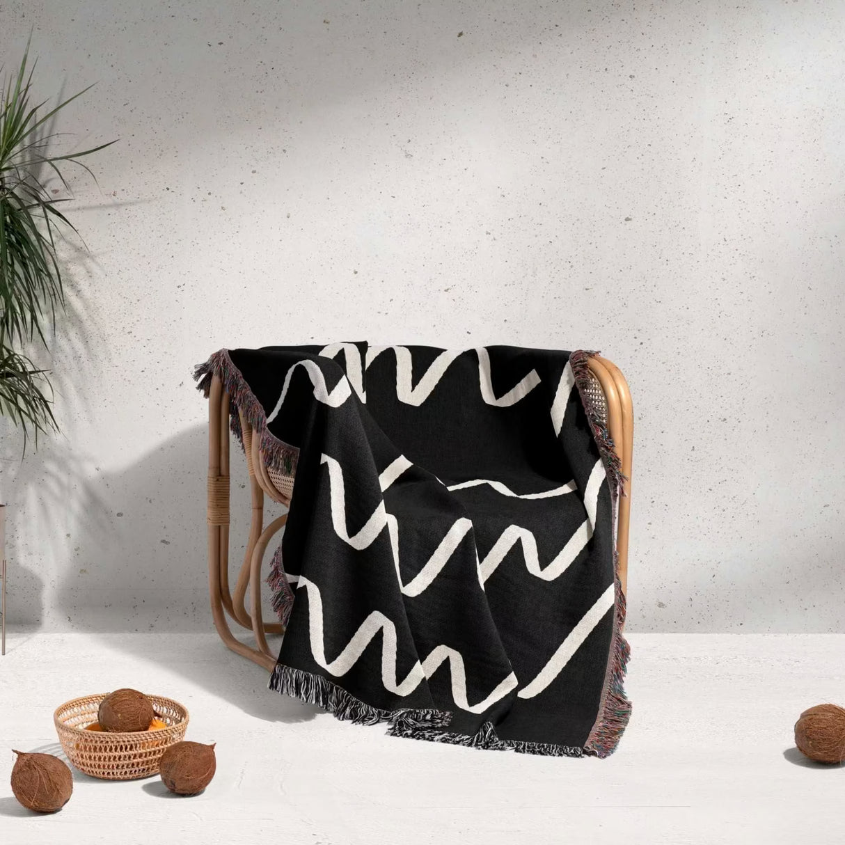 Black and white accent decorative woven blanket throw tapestry draped over a chair with a minimal background