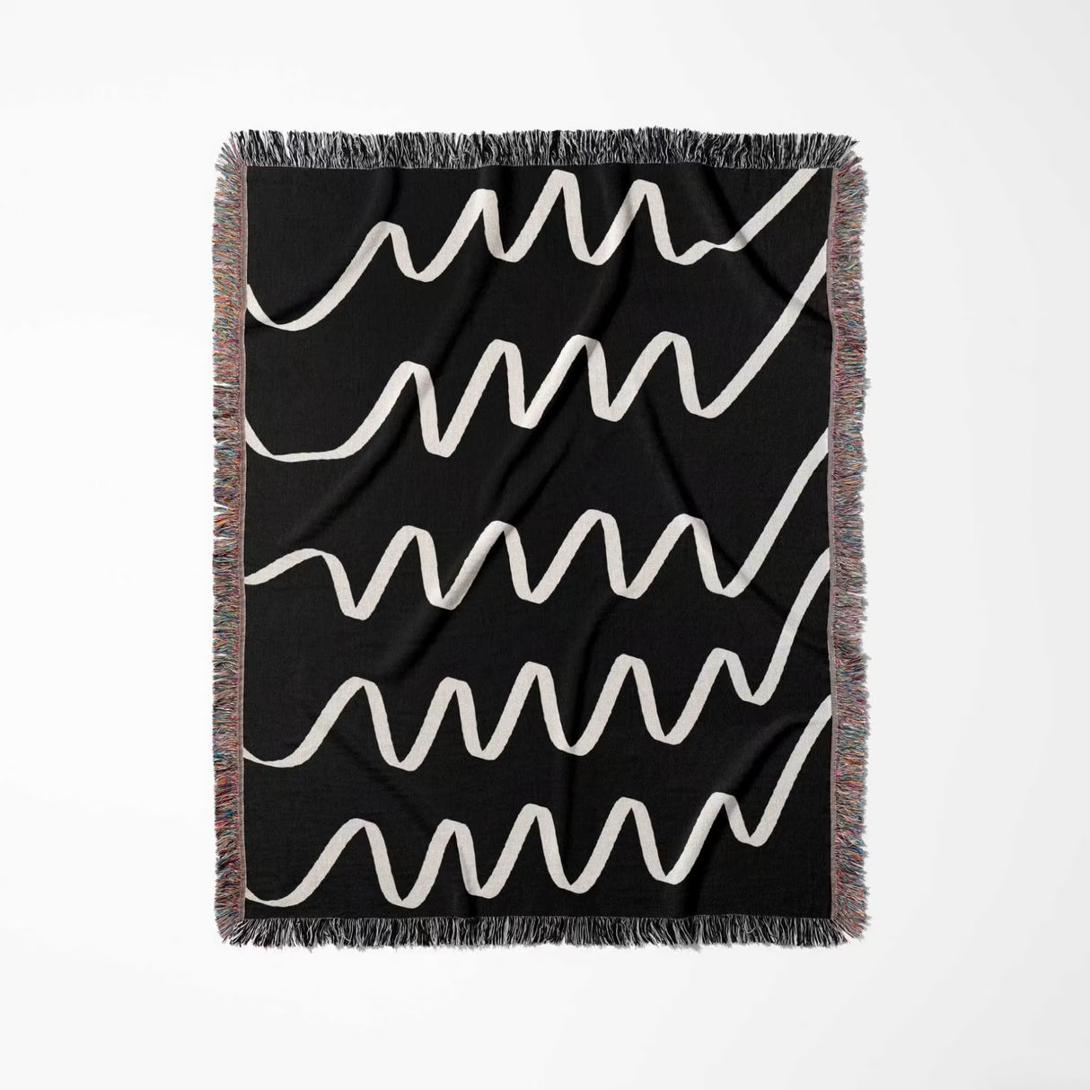 Black and white accent decorative woven blanket throw tapestry with white wavy lines and multicolored fringe full view on a light gray background
