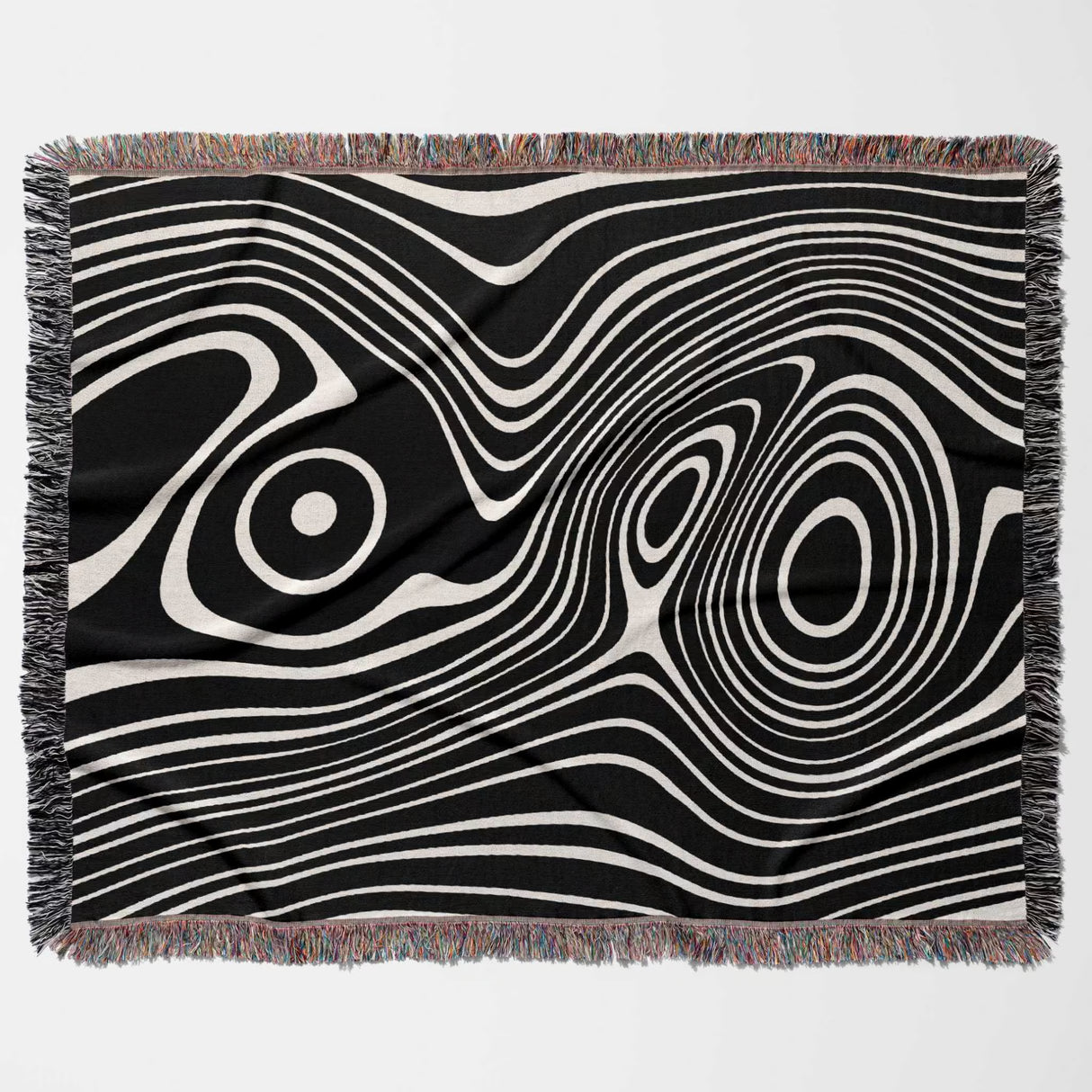 Black and white abstract woven throw blanket with fringe on a light gray background