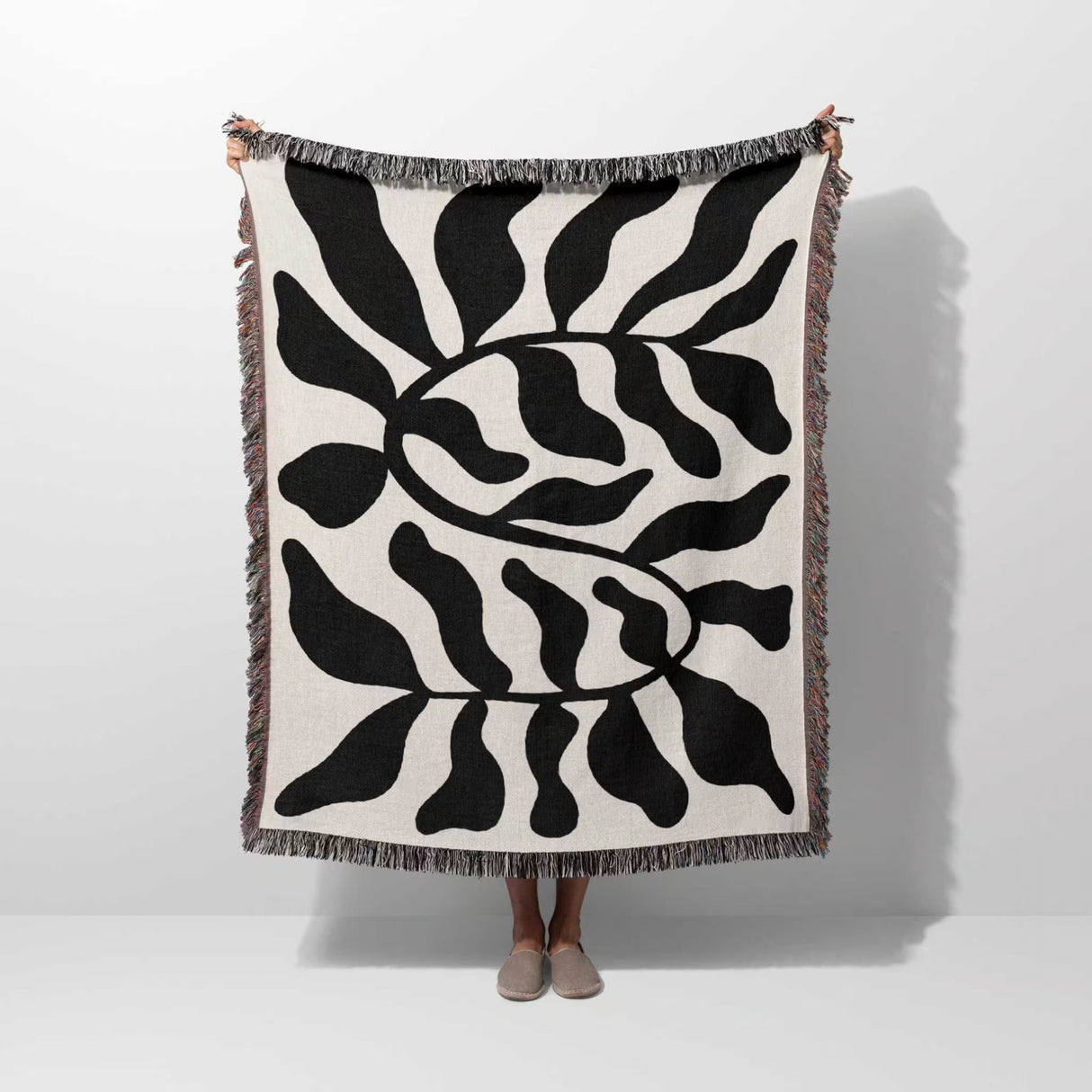 Black leaf Matisse throw blanket held by a person on a white background