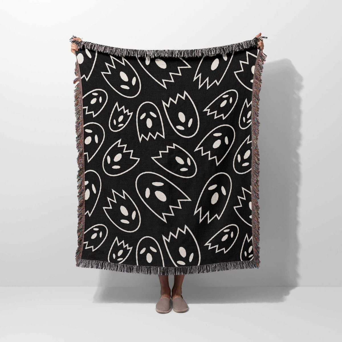 Black blanket with white abstract patterns draped over a person on a white background