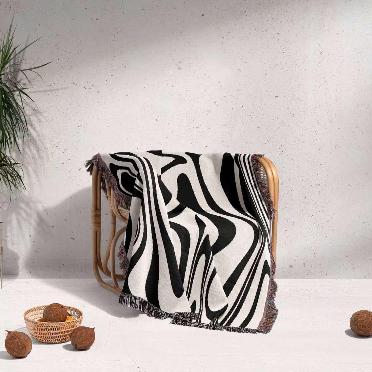 Black and white marble woven throw blanket draped over a chair against a light gray wall.