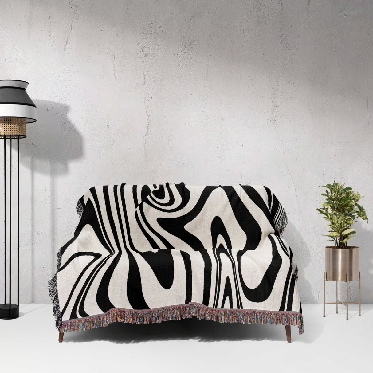 Black and white marble woven throw blanket on a sofa against a white wall.