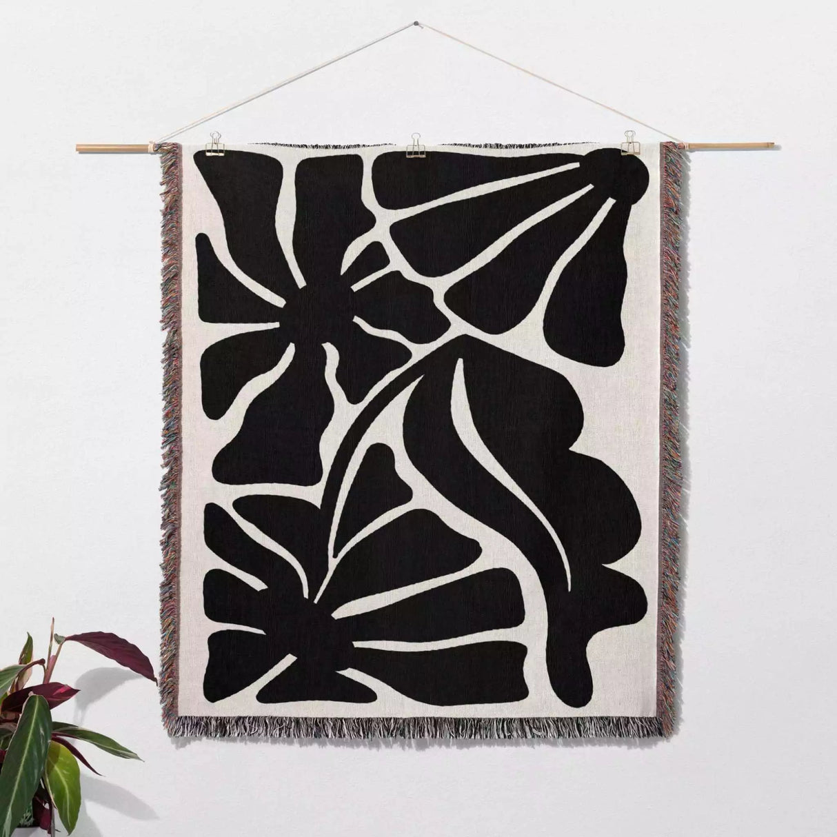 Black and white Matisse flowers woven throw blanket as woven wall art with black abstract leaf patterns on a white background