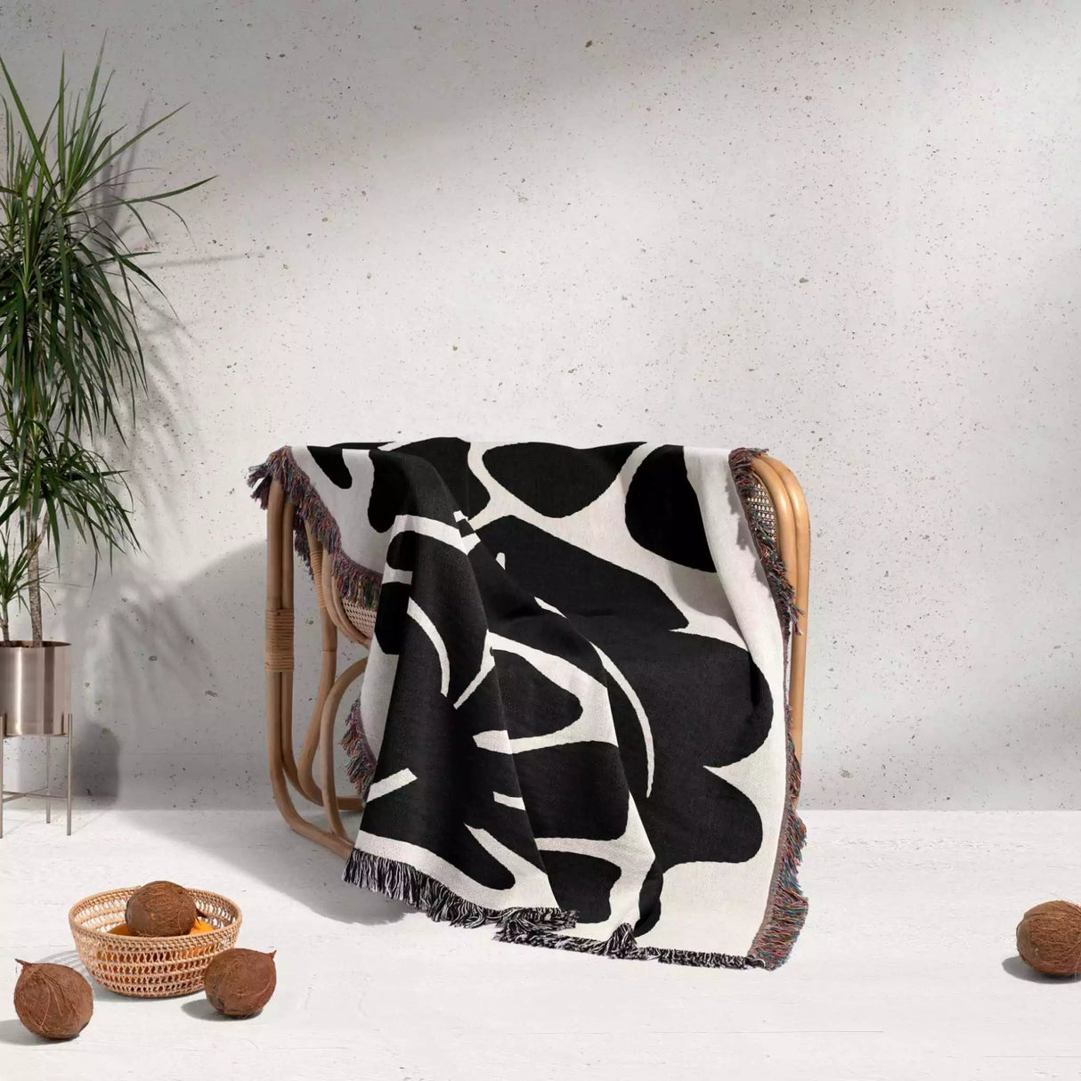 Black and white Matisse flowers woven throw blanket patterned draped over a chair with a minimal background