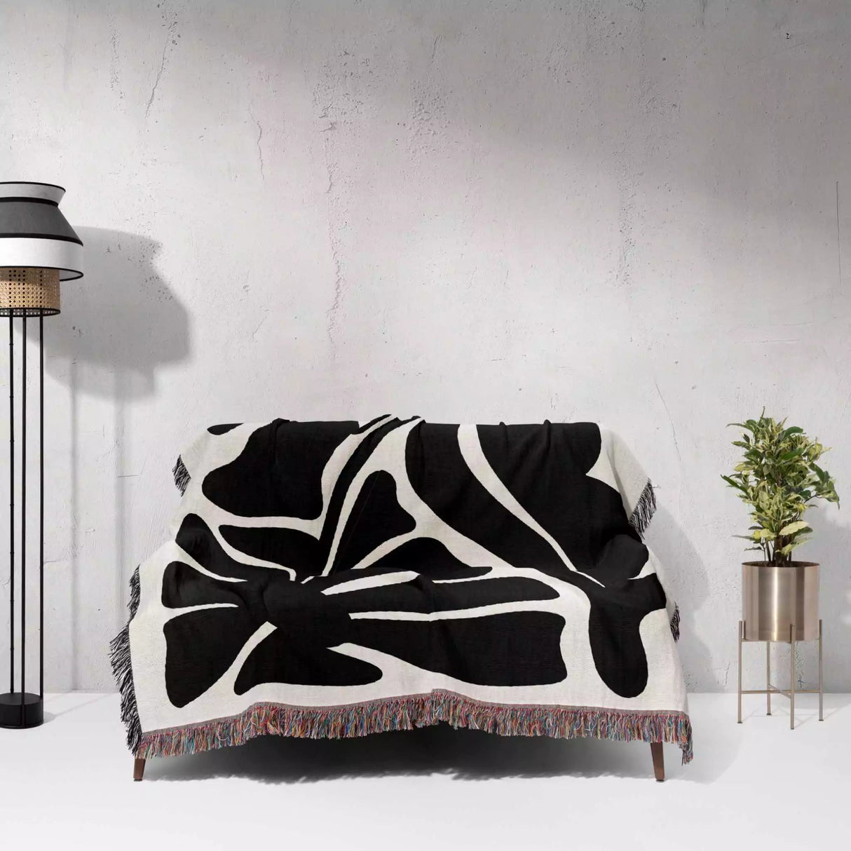 Black and white Matisse flowers woven throw blanket draped over a chair against a light gray wall.