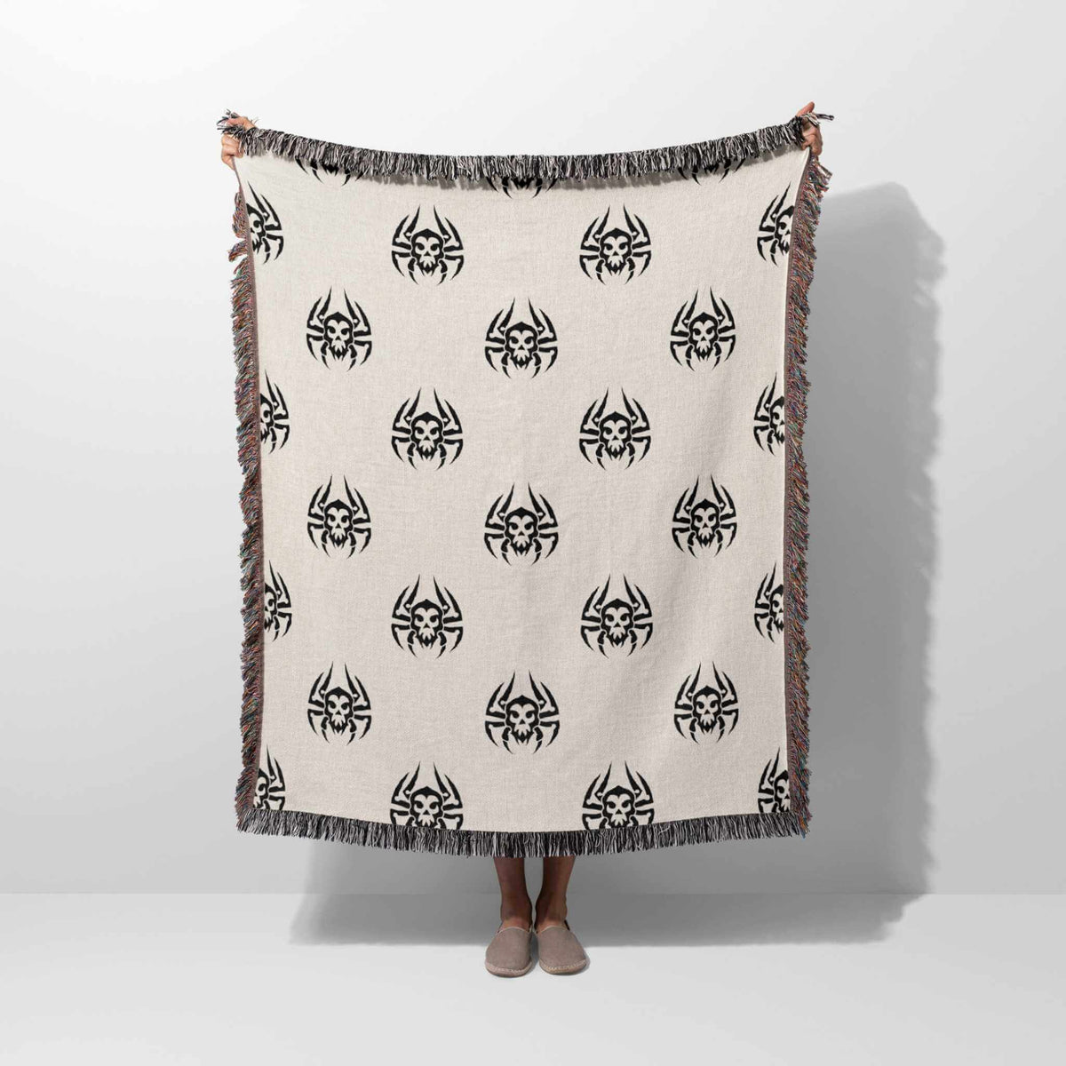 Person holding a blanket with black spider patterns on a white background