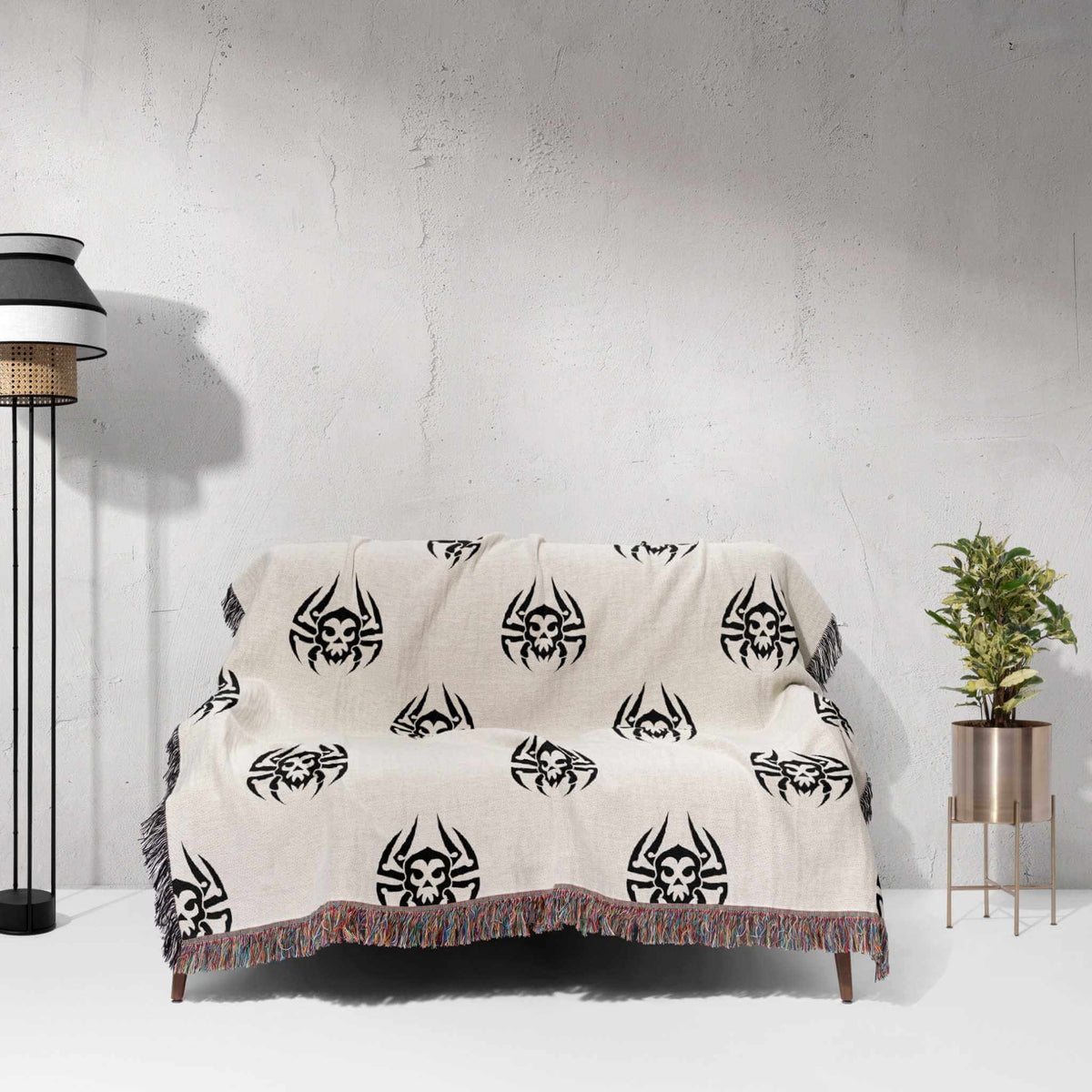 Beige blanket with black tribal patterns draped over a chair against a white wall.