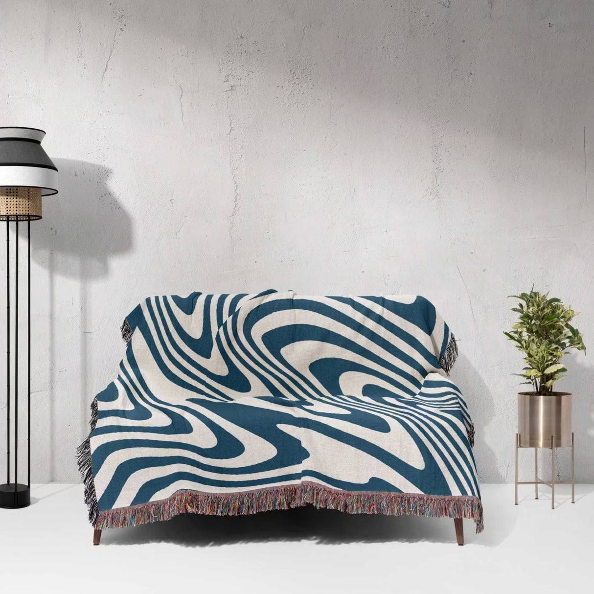 Blue cotton modern decorative woven throw blanket draped over a couch against a white wall.