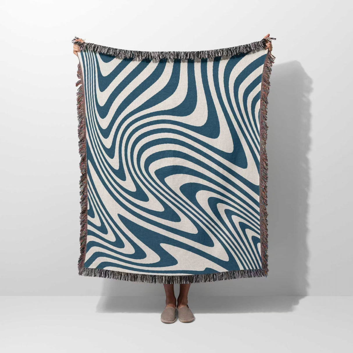 Person holding a blue cotton modern decorative woven throw blanket against a white background