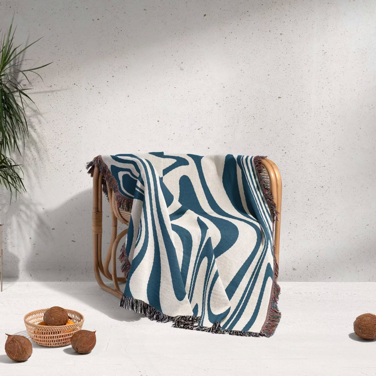 Decorative blue marble woven throw blanket for couch with abstract pattern draped over a chair against a white wall.