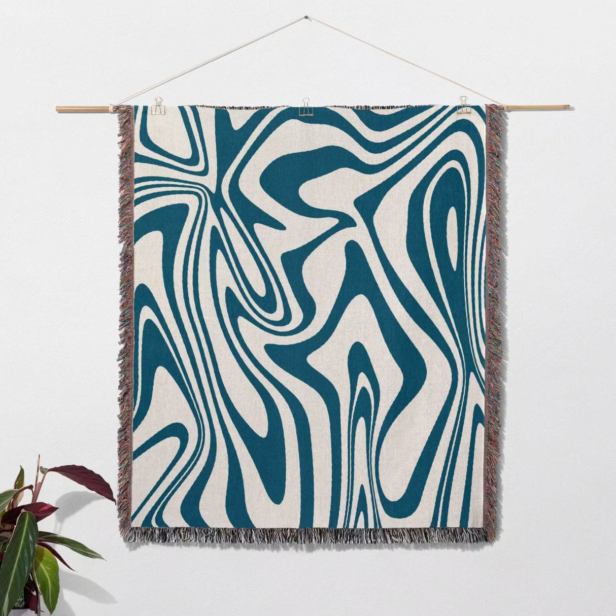 Blue marble woven throw blanket for couch with abstract blue and white pattern hanging on a white wall.