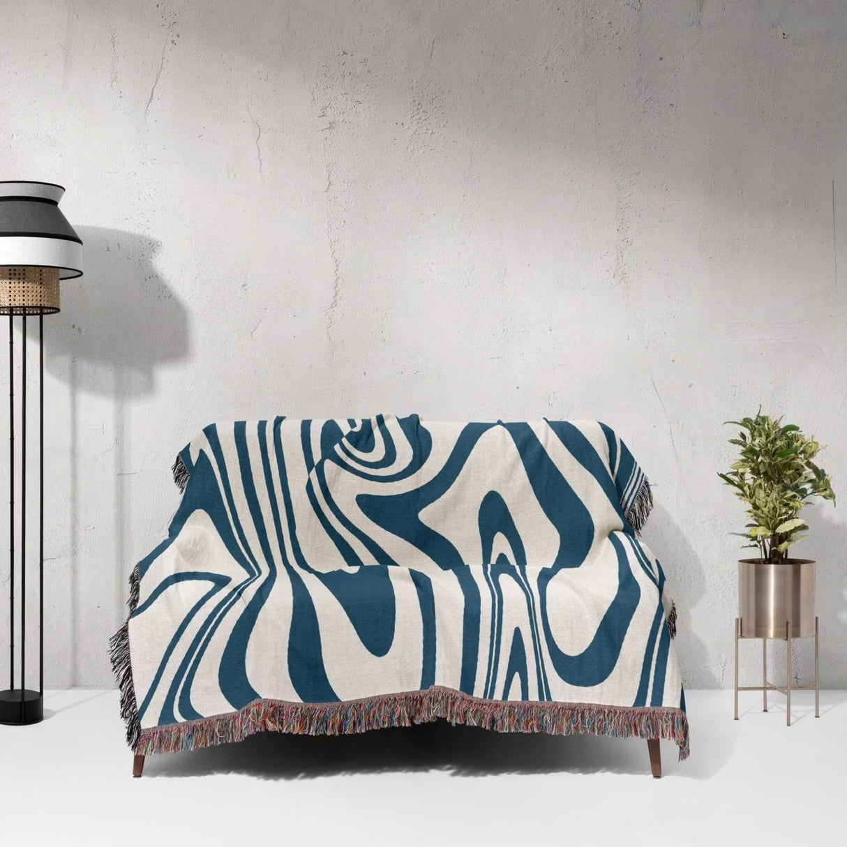 Sofa with a blue marble woven throw blanket for couch against a white wall.