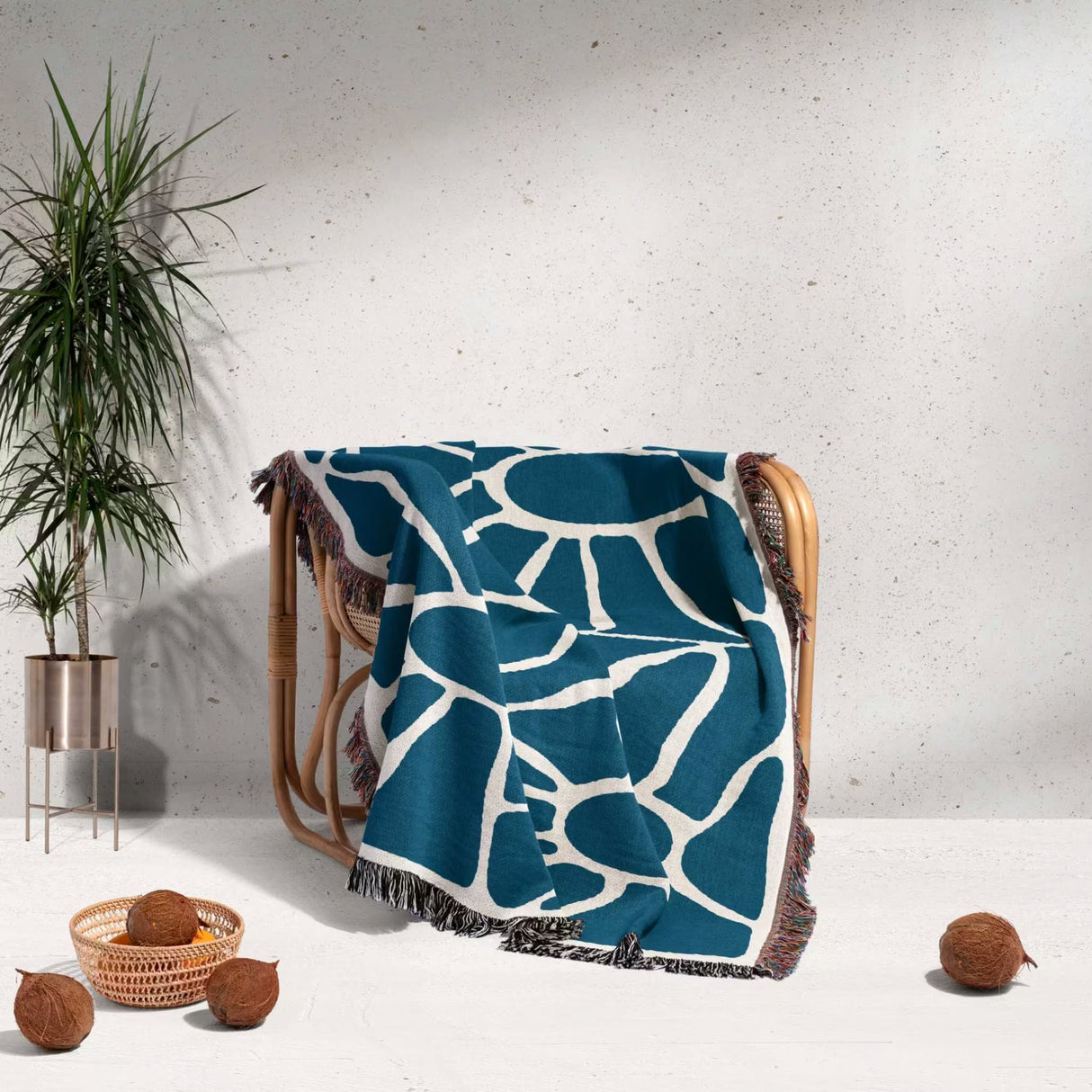 Blue Matisse tapestry throw blanket for couch and bed draped over a chair against a light gray wall.