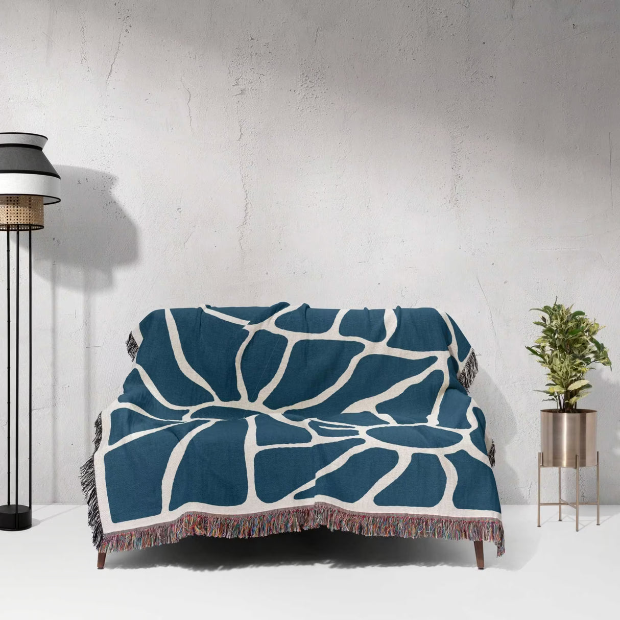 Blue Matisse tapestry throw blanket for couch and bed draped over a couch against a light gray wall.