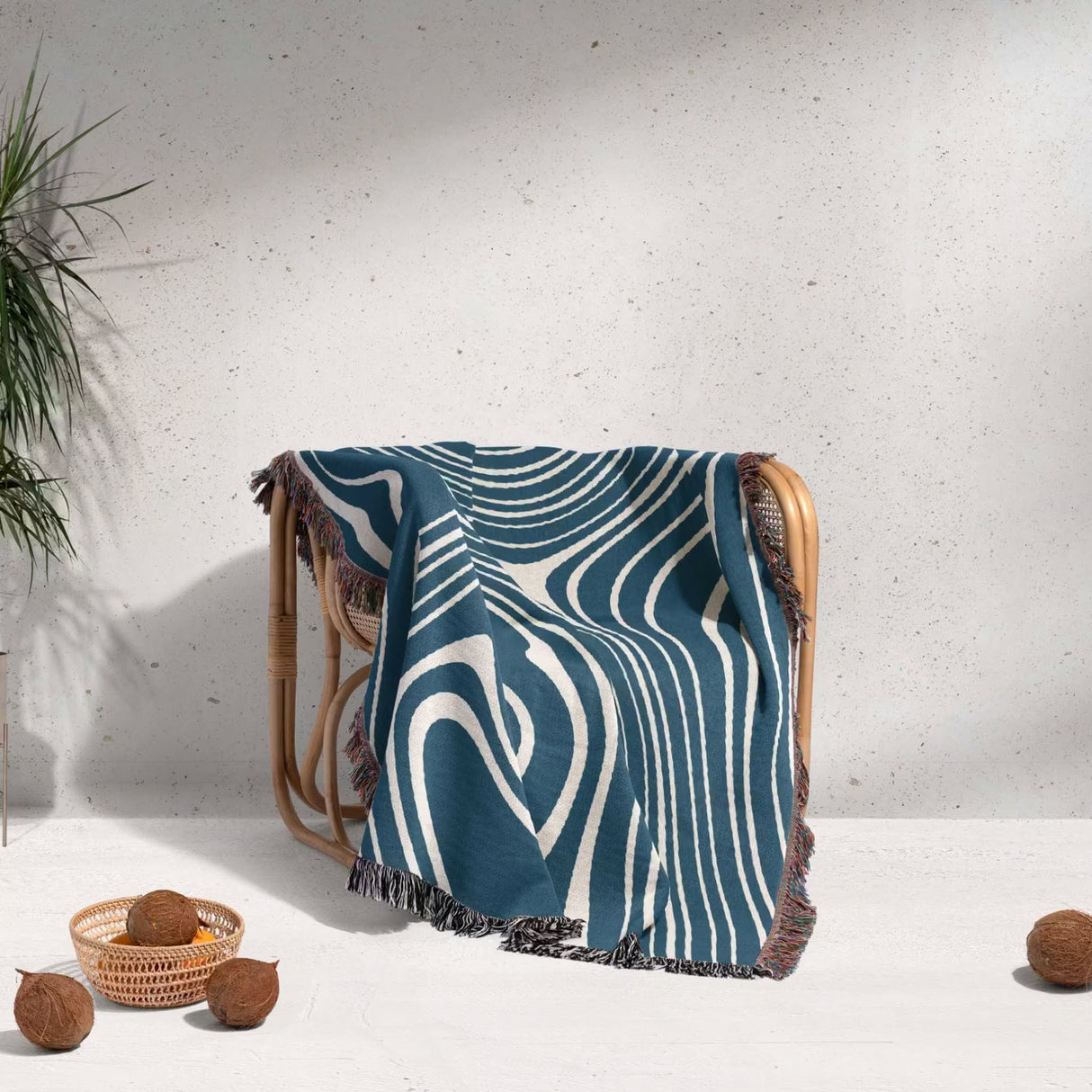 Blue trendy abstract woven throw blanket draped over a wooden chair against a light gray wall.