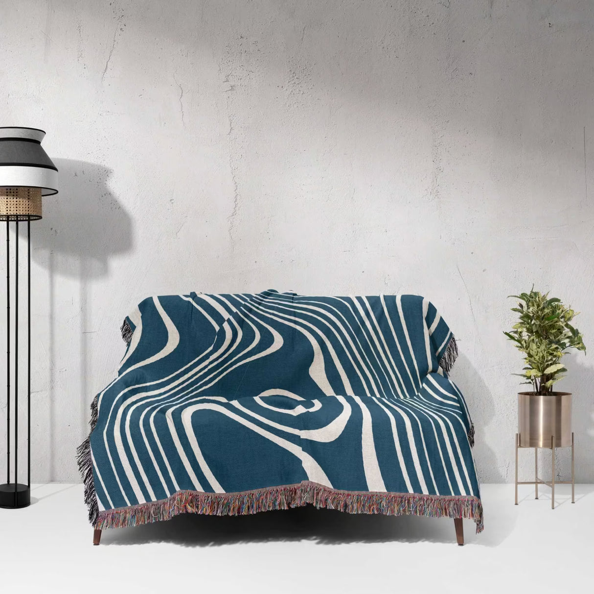 Blue trendy abstract woven throw blanket draped over a couch against a white wall.