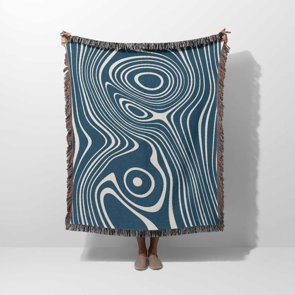 Person holding a blue trendy abstract woven throw blanket against a white background