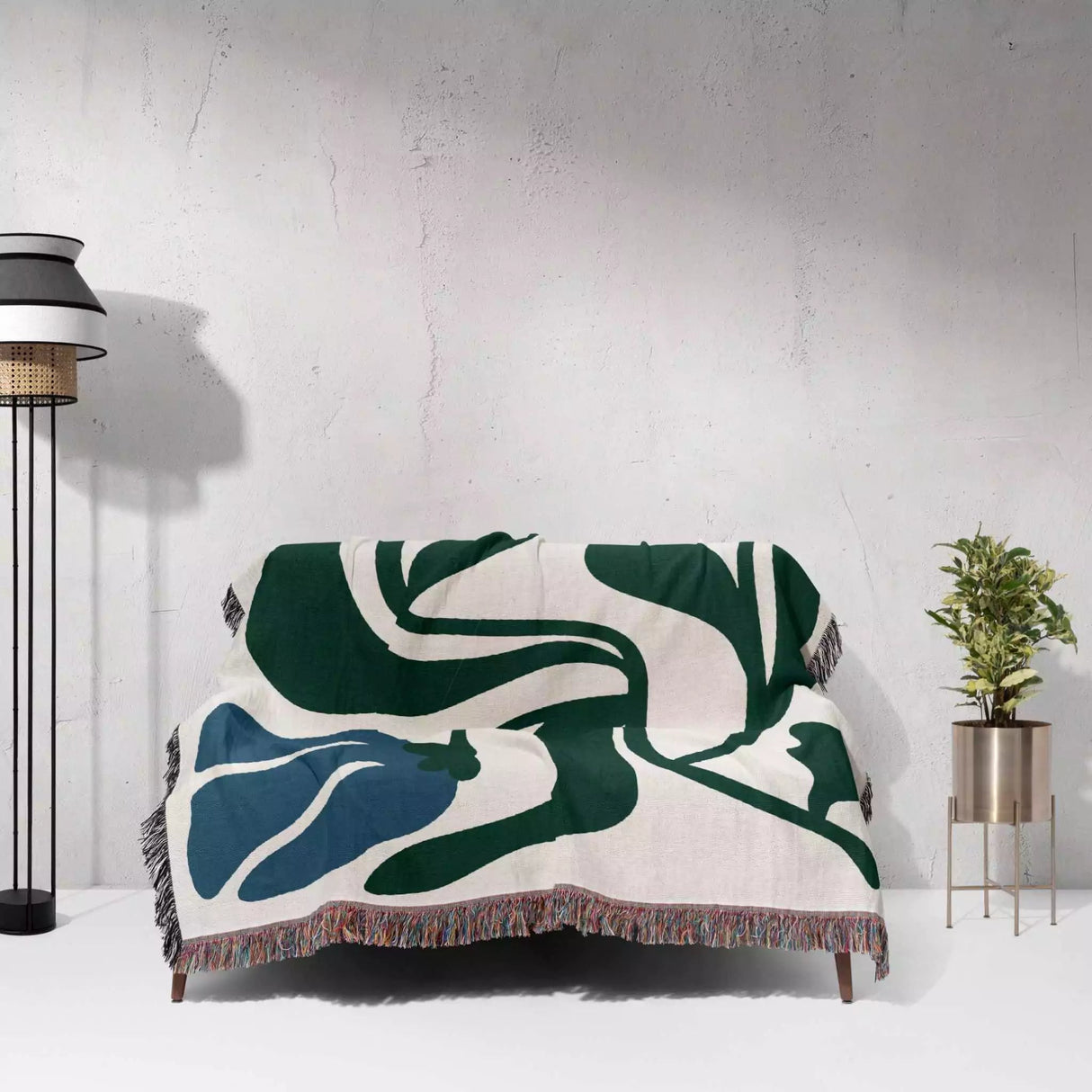 Abstract patterned blanket blue and green Matisse flower woven throw blanket draped over a chair against a white wall.
