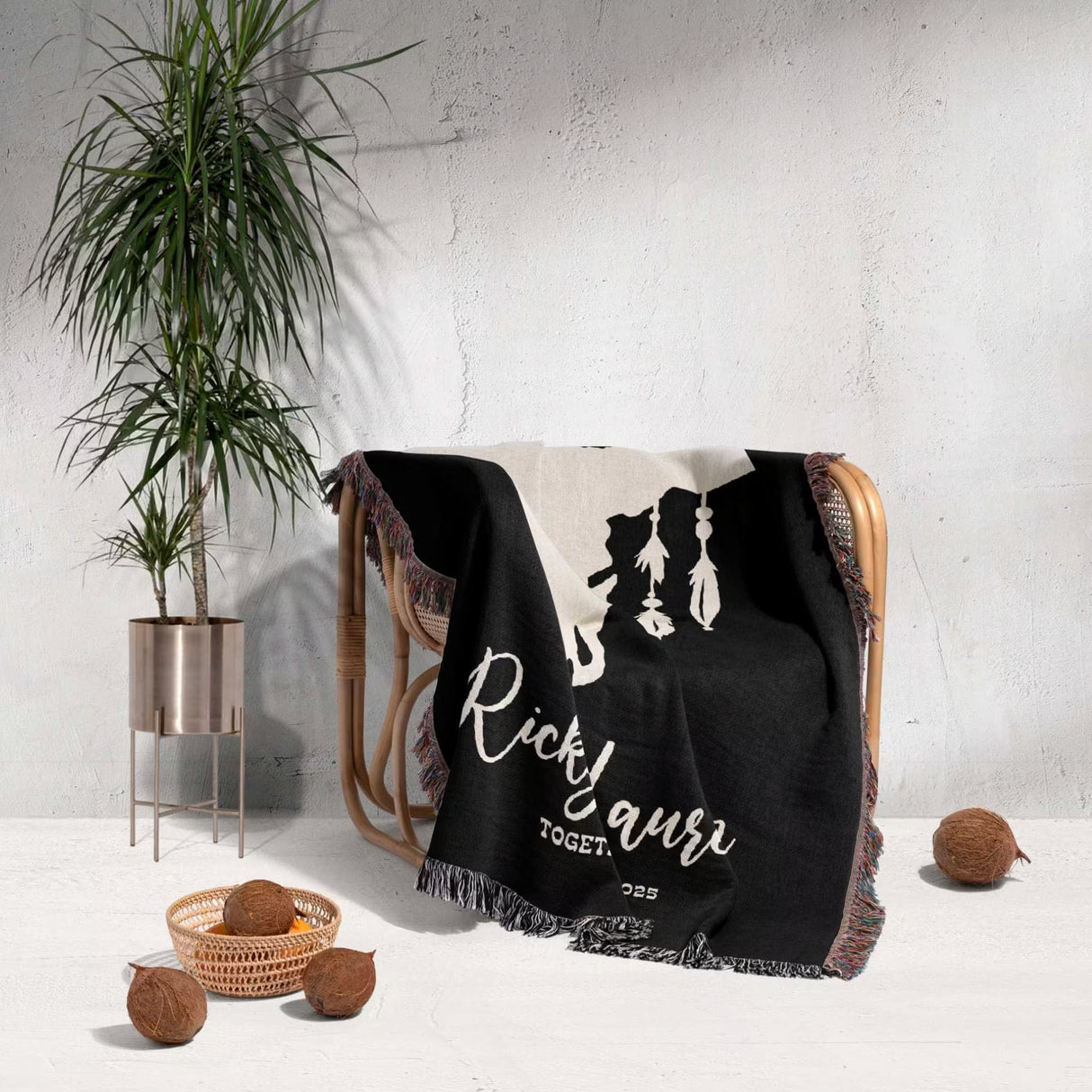 Bull skull boho wedding 2nd anniversary gift woven throw blanket with white text draped over a chair next to a plant and coconuts on a light gray background