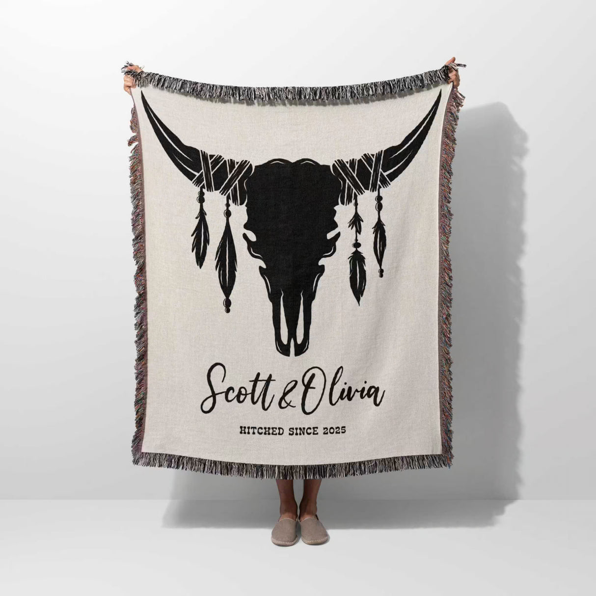 Cow skull wedding cotton anniversary gift woven throw blanket with bull skull design and text held by a person on a white background