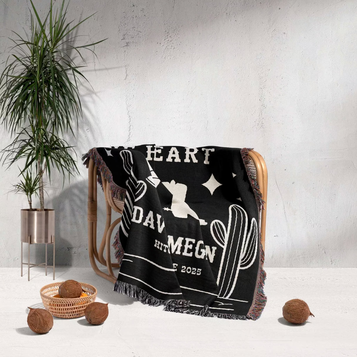Cowboy boots wedding 2nd anniversary gift woven throw blanket with white text and graphics draped over a chair, with a plant and coconuts in the background.