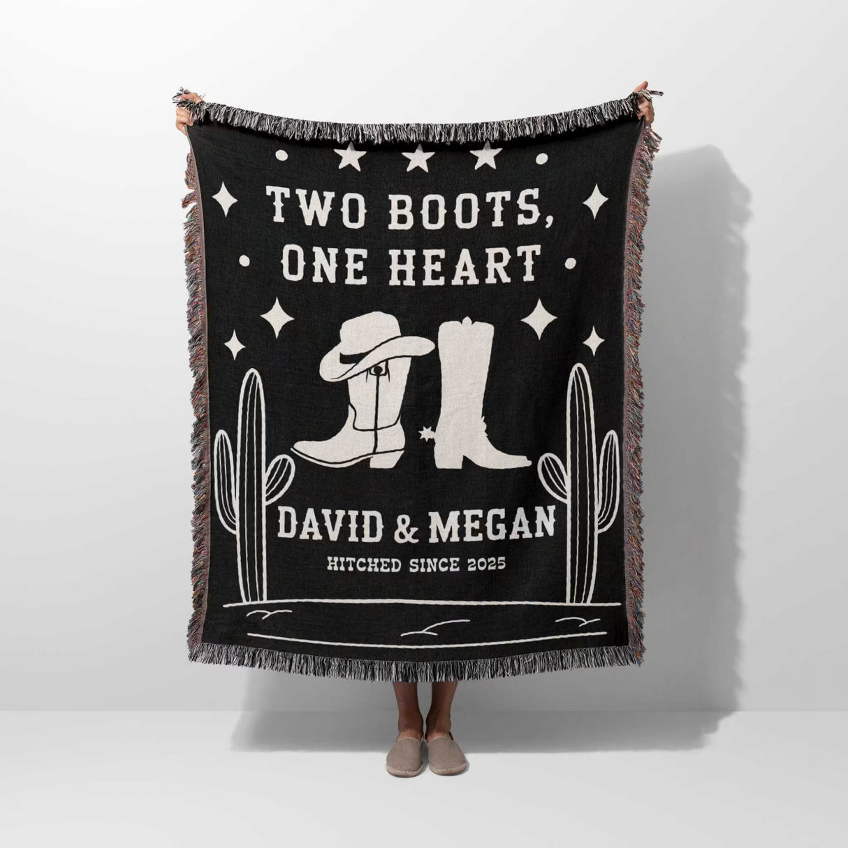 Cowboy boots wedding 2nd anniversary gift woven throw blanket with white text and graphics, featuring cowboy boots and cacti, held by a person.
