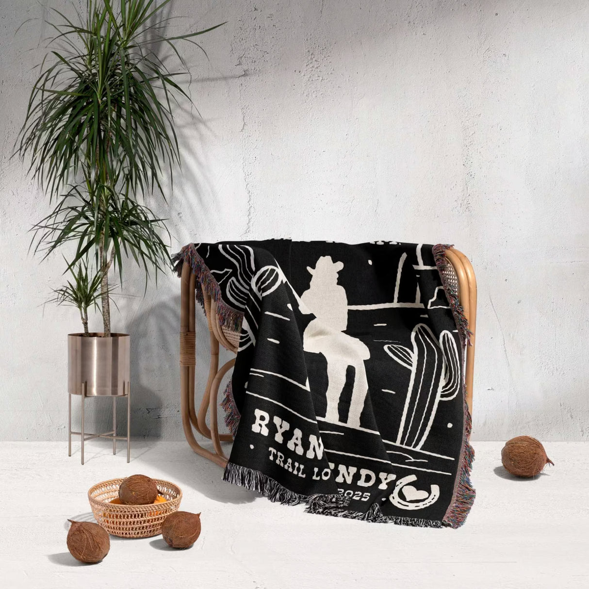 Cowboy and cowgirl western 2nd anniversary gift woven throw blanket with white graphics and text draped over a chair, with a plant and decorative items in the background.