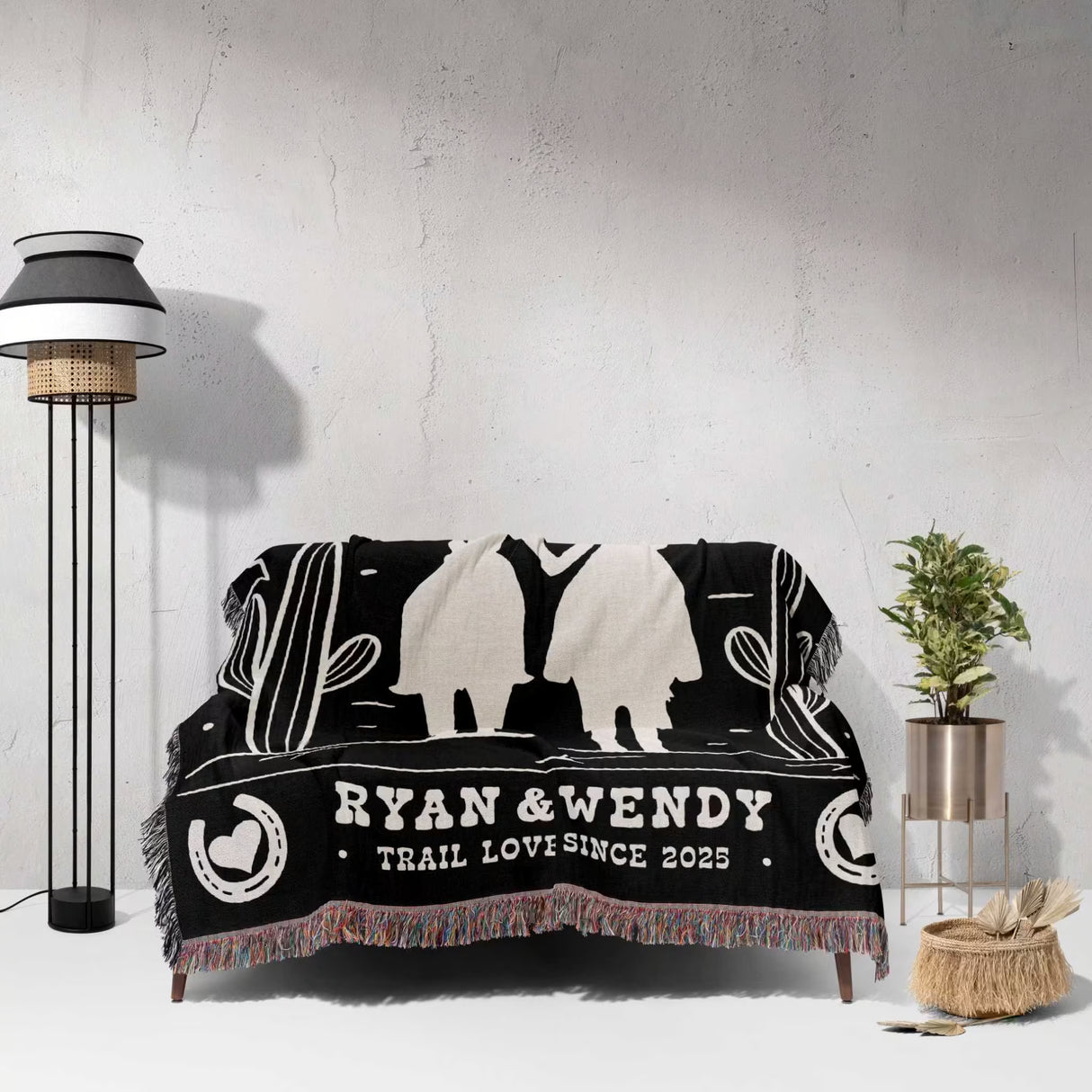 Cowboy and cowgirl western 2nd anniversary gift woven throw blanket with white designs and text on a couch against a light gray wall.