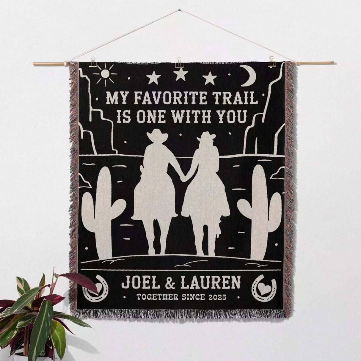 Cowboy and cowgirl on two horses 2nd anniversary gift woven throw blanket as a wall hanging with desert scene design, couple holding hands, and text 'My favorite trail is one with you' by Joel & Lauren.