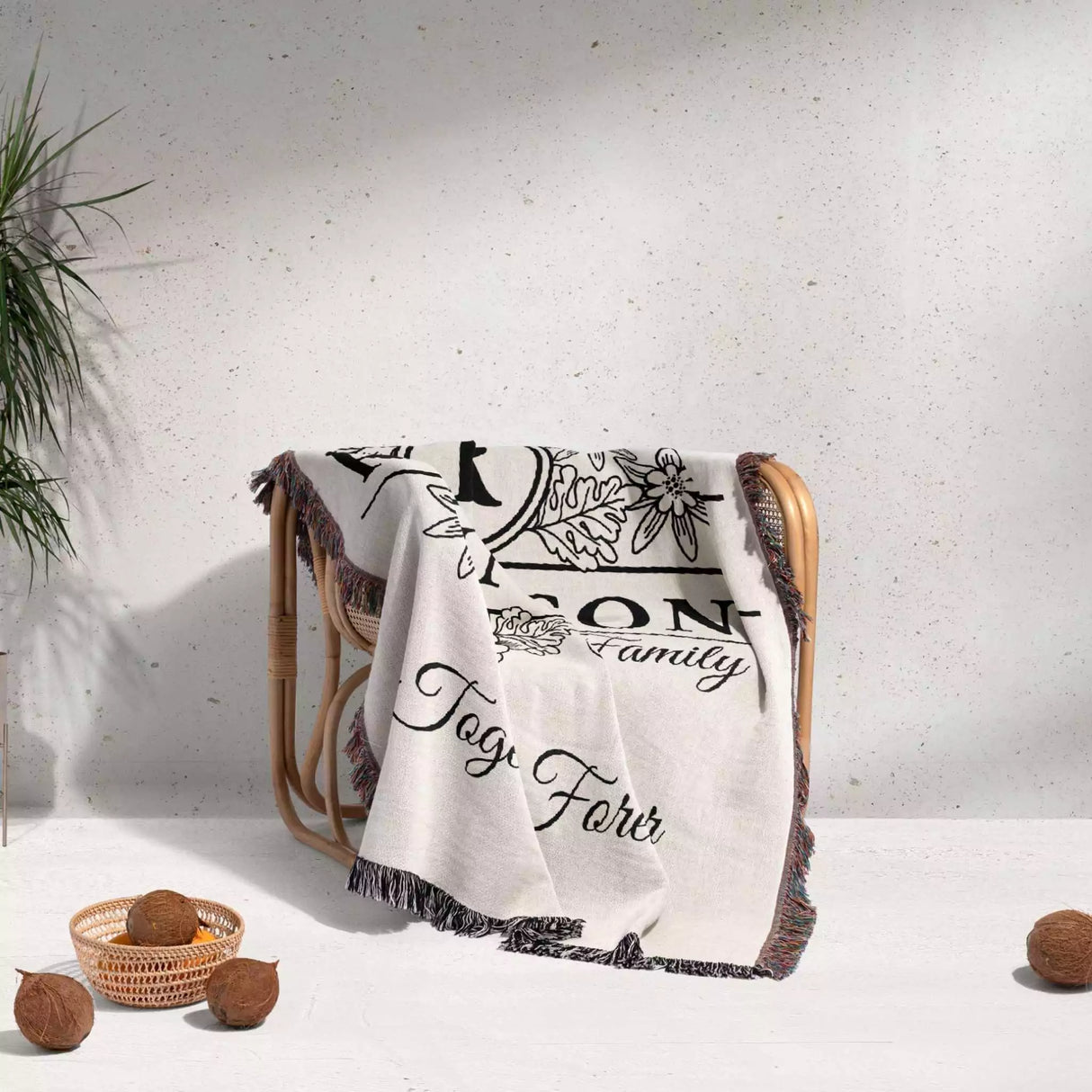 Custom last name cotton blanket with text and graphics draped over a chair on a light background