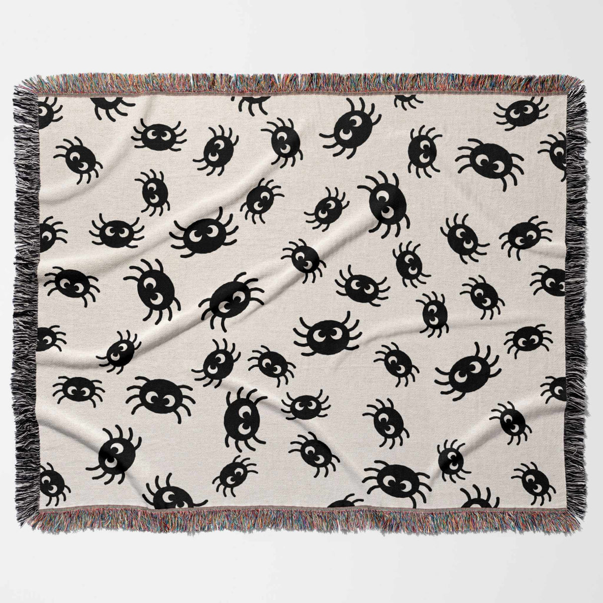 Cute spiders woven throw blanket for Halloween décor flat lay on a beige background.
