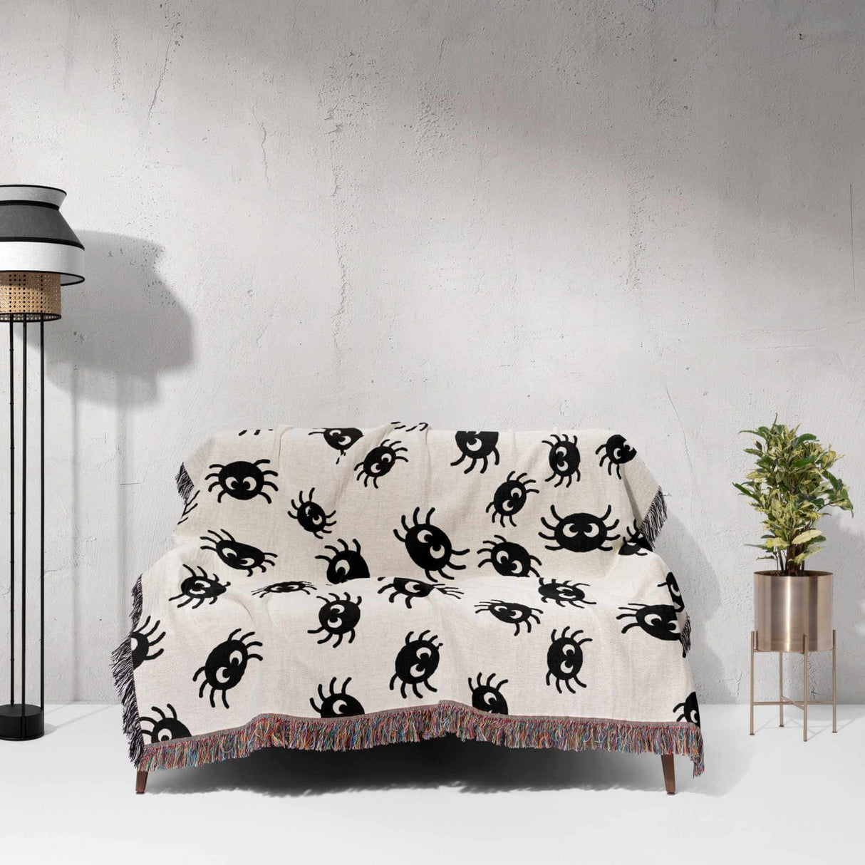 Cute spiders woven throw blanket for Halloween décor draped over a chair against a white wall.