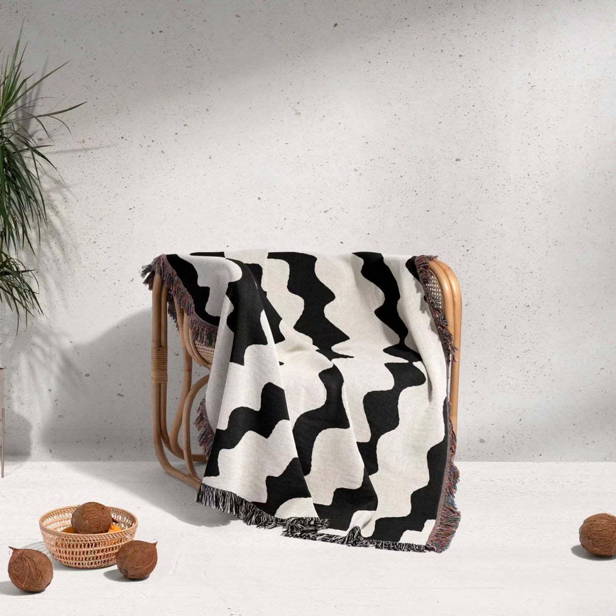 Black and white decorative abstract wavy woven blanket throw over a wooden chair against a light gray wall.