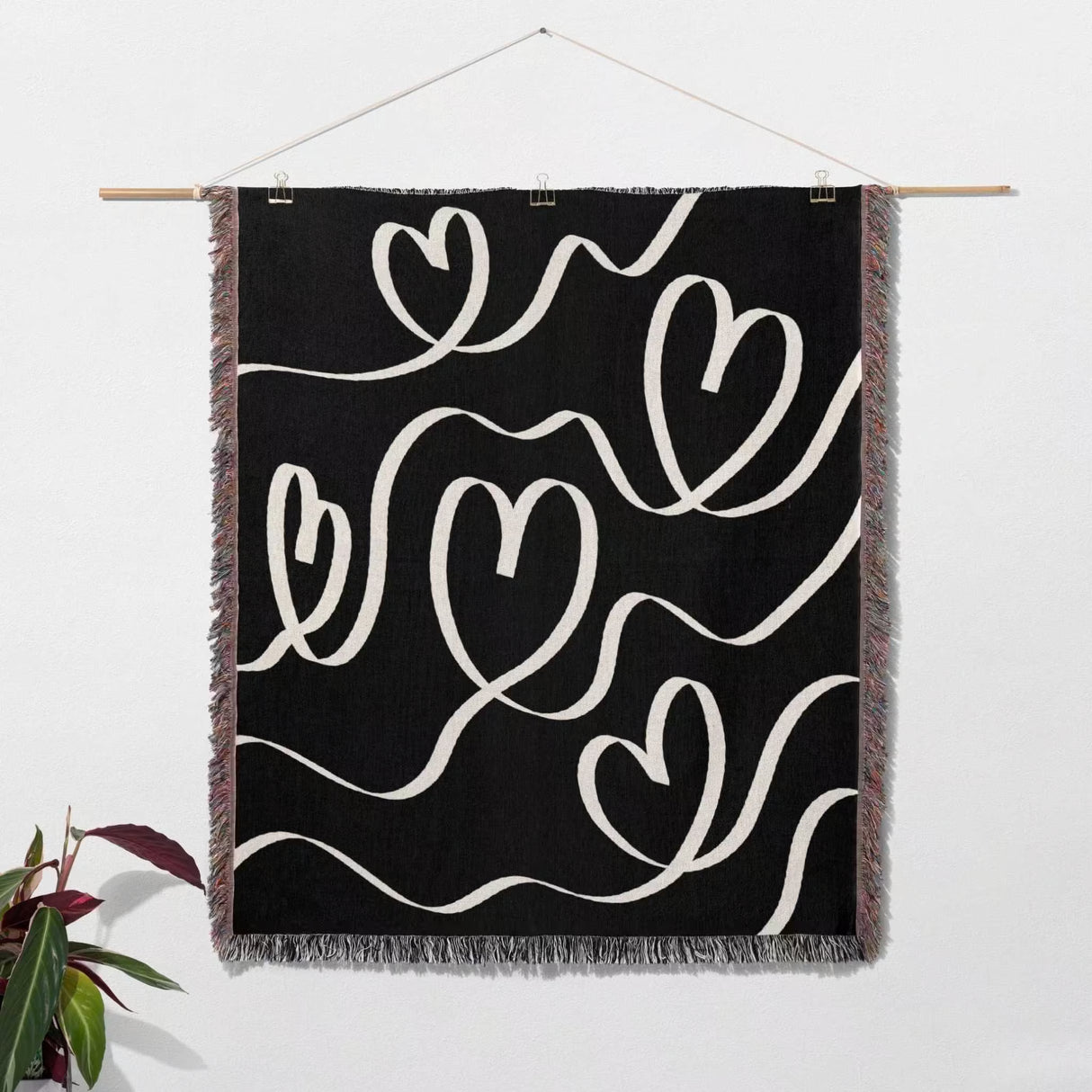Black and white decorative hearts woven blanket throw as wall art hanging on a wall