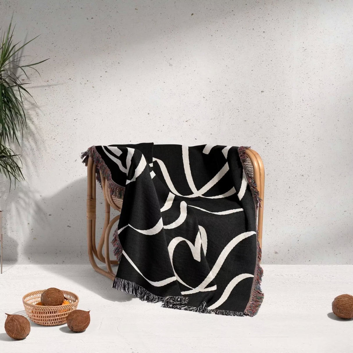 Black and white decorative hearts woven blanket throw over a chair with a minimal background