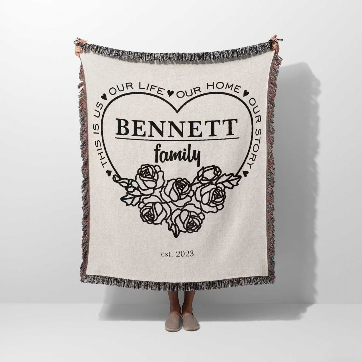 Family name personalized woven throw blanket gift for spouse with 'Bennett family' design held by a person on a white background