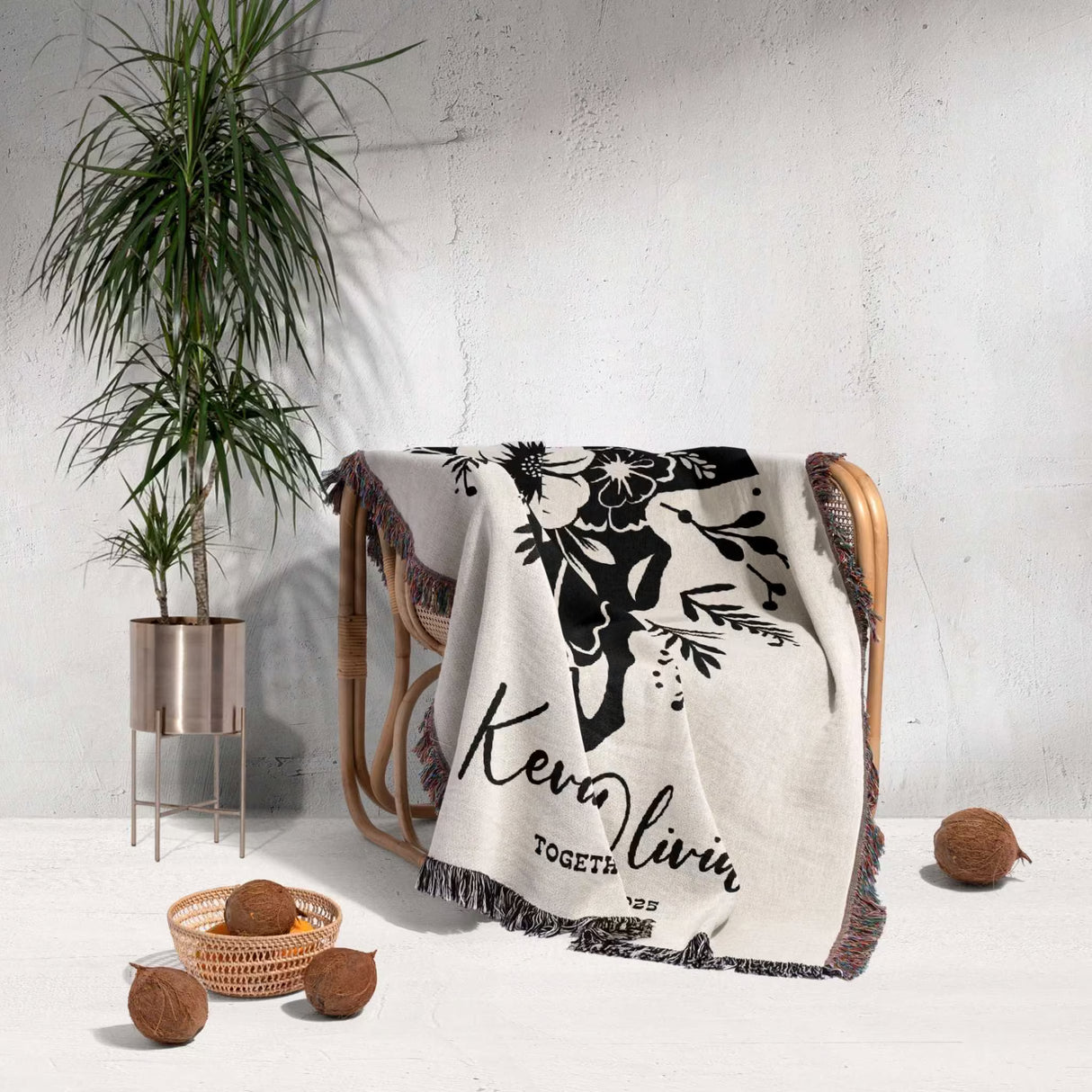 Floral cow skull cotton anniversary gift woven throw blanket with black floral design and text draped over a chair in a room with a plant and decorative items.