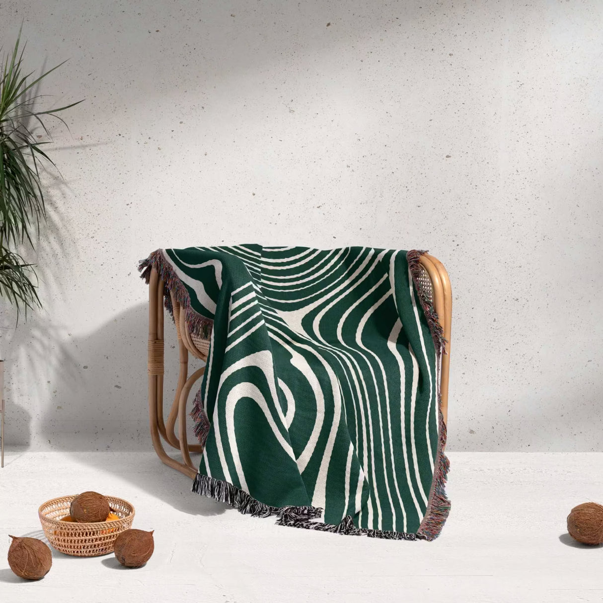 Forest green abstract woven throw blanket over a wooden chair against a light gray wall.
