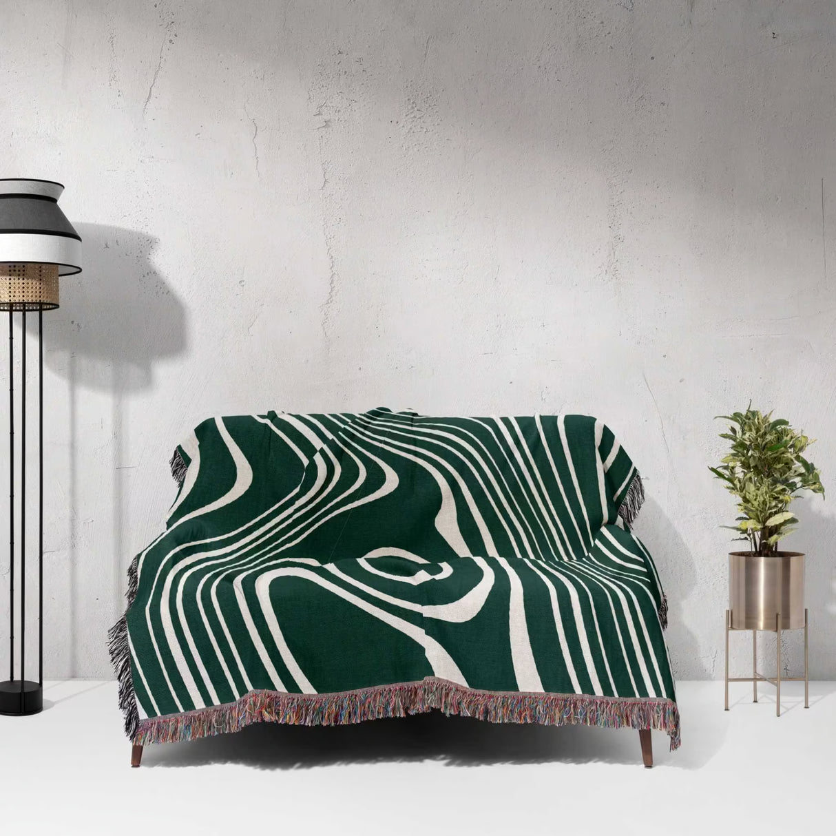 Forest green abstract woven throw blanket draped over a couch against a light gray wall.