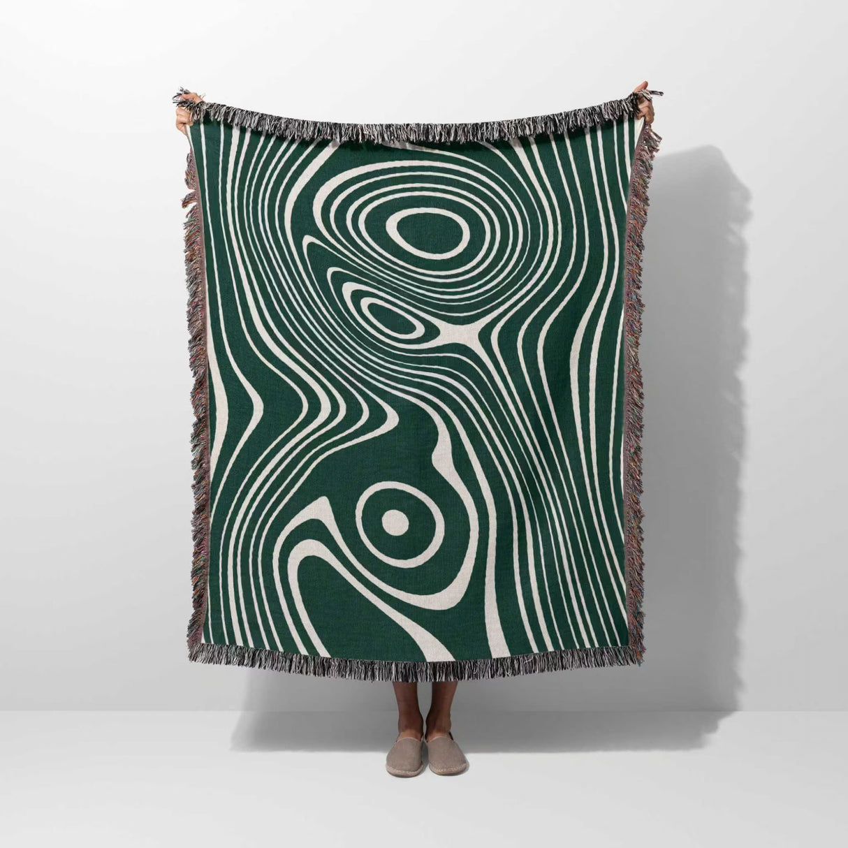 Person holding a forest green abstract woven throw blanket against a white background