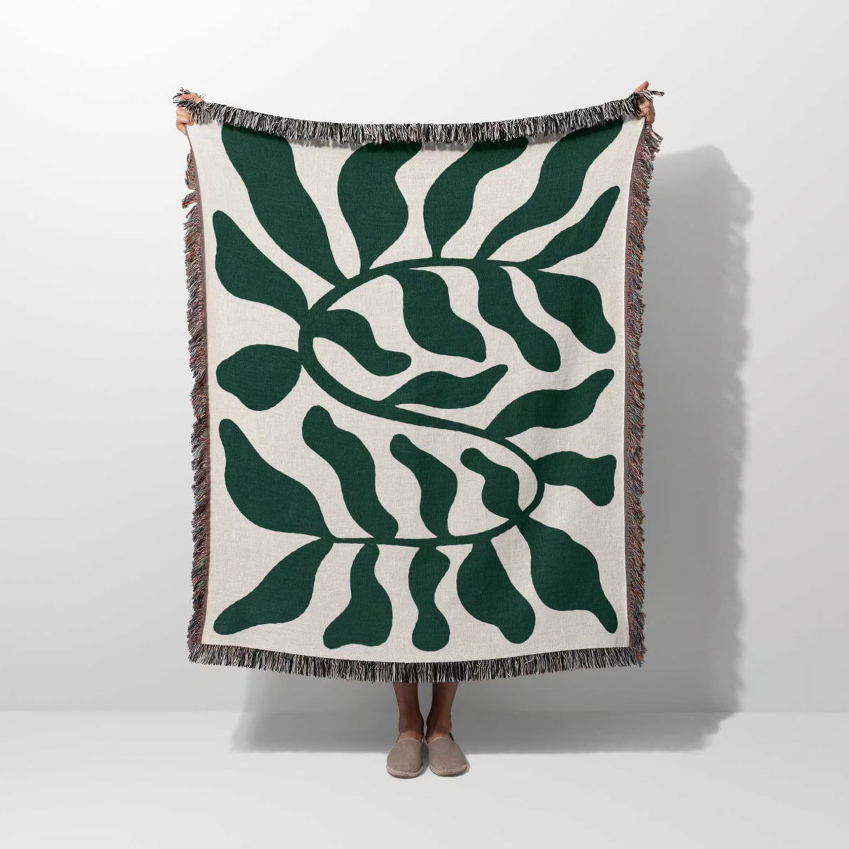 Forest green leaf Matisse throw blanket held by a person on a white background
