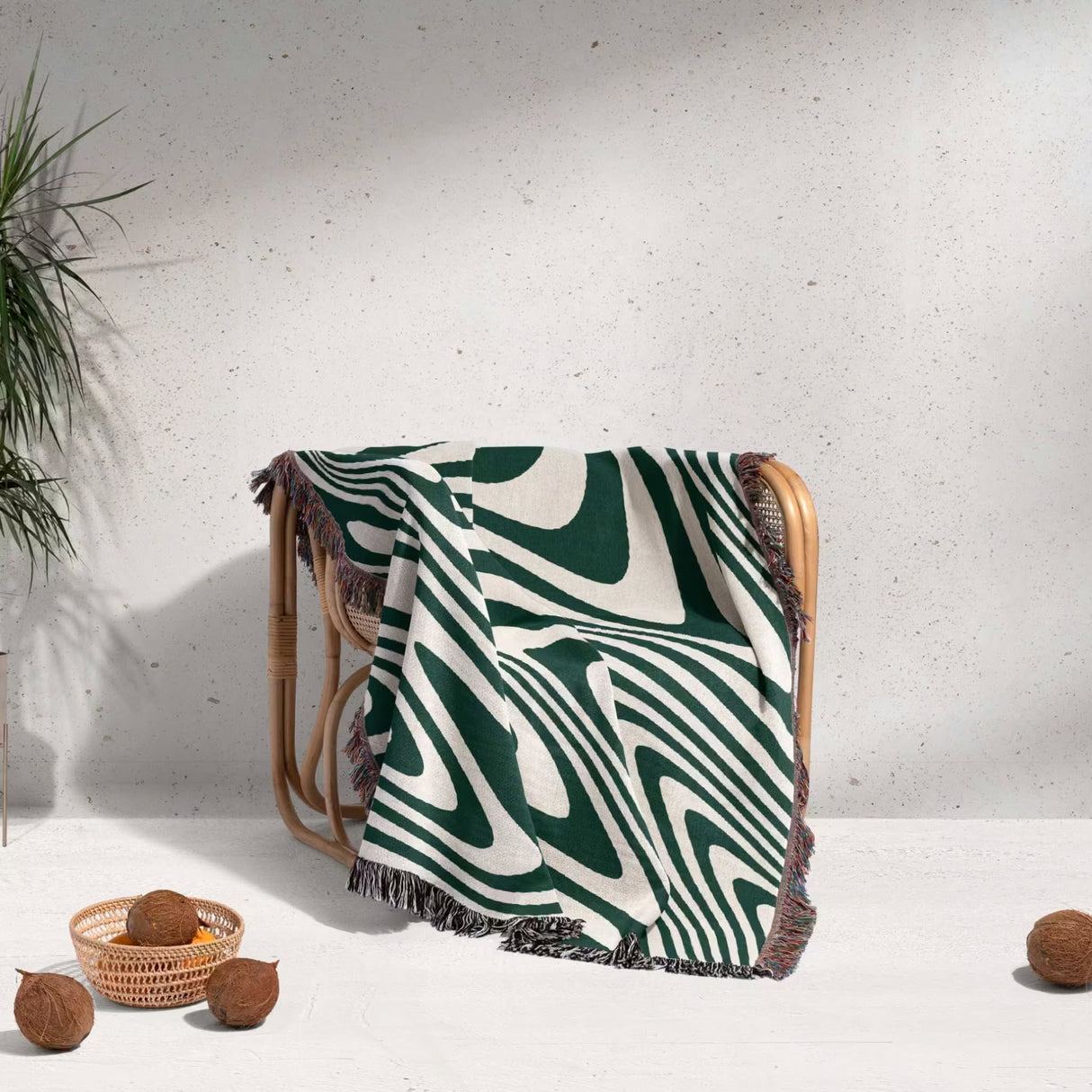 Forest green modern decorative woven throw blanket draped over a wooden chair against a light gray wall.